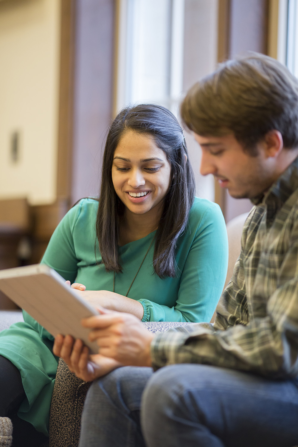 Two students sitting together looking at a notebook